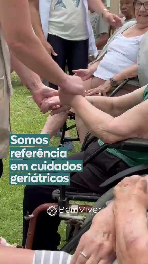 Mãos de profissional apoiando as mãos de uma idosa durante o cuidado